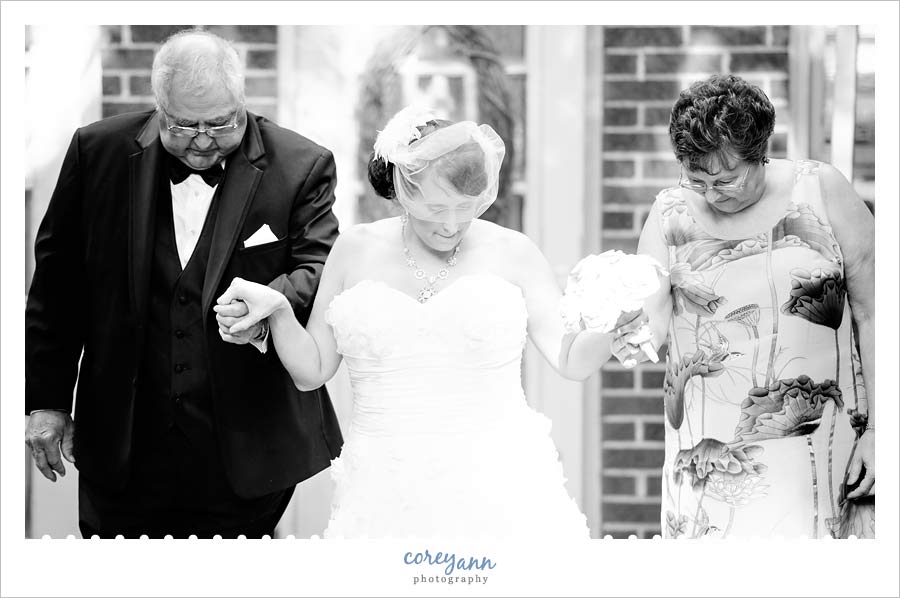 bride with both parents walking down the aisle
