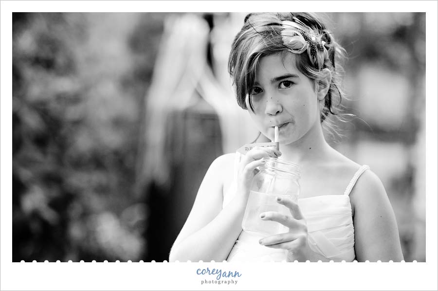 flower girl sipping out of a mason jar with custom flag during reception