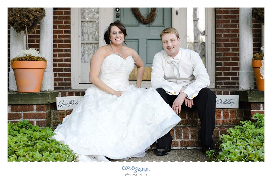 bride and groom sitting on steps in front of their new home