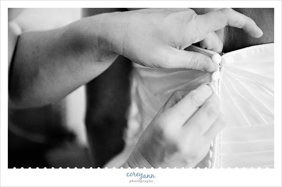 matron of honor helping button up bride's dress