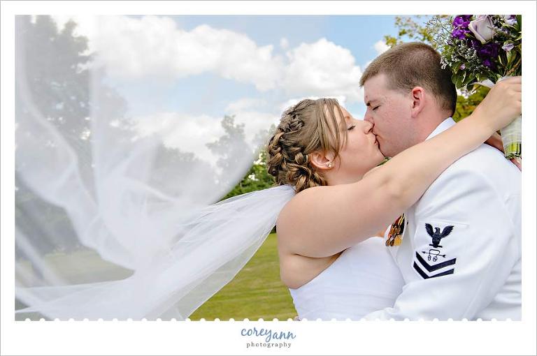bride and groom in navy dress uniform kissing in ohio
