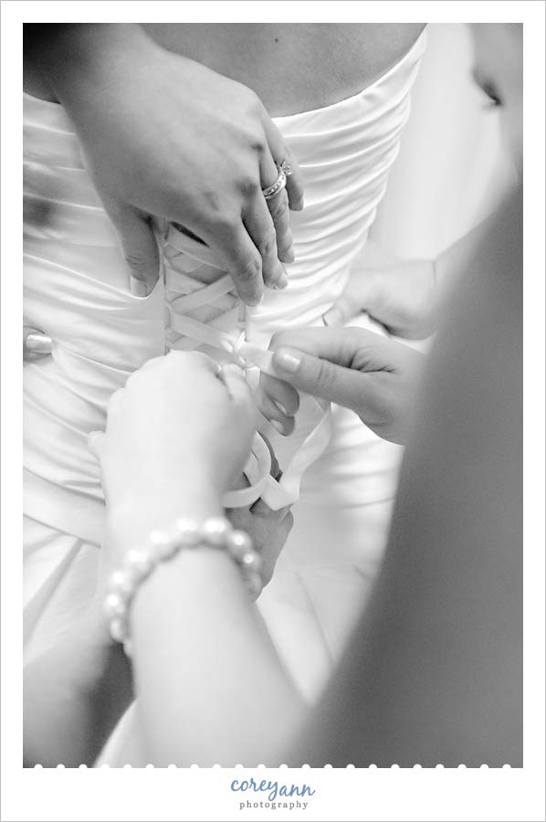 Stephanie and Mark's Wedding bridesmaids doing up corset back of bridal gown