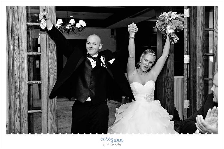 bride and groom cheer during entrance into wedding reception at portage country club