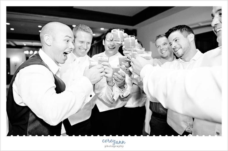 groom and groomsman doing a shot during wedding reception at portage country club