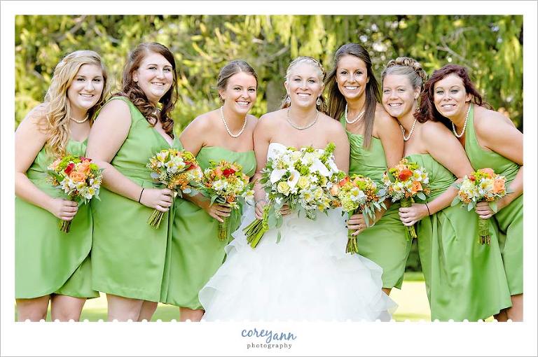 bridesmaids with green dresses and orange flower bouquets
