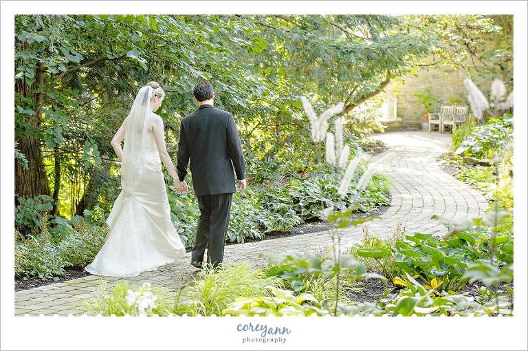 bride and groom walking a wooded path