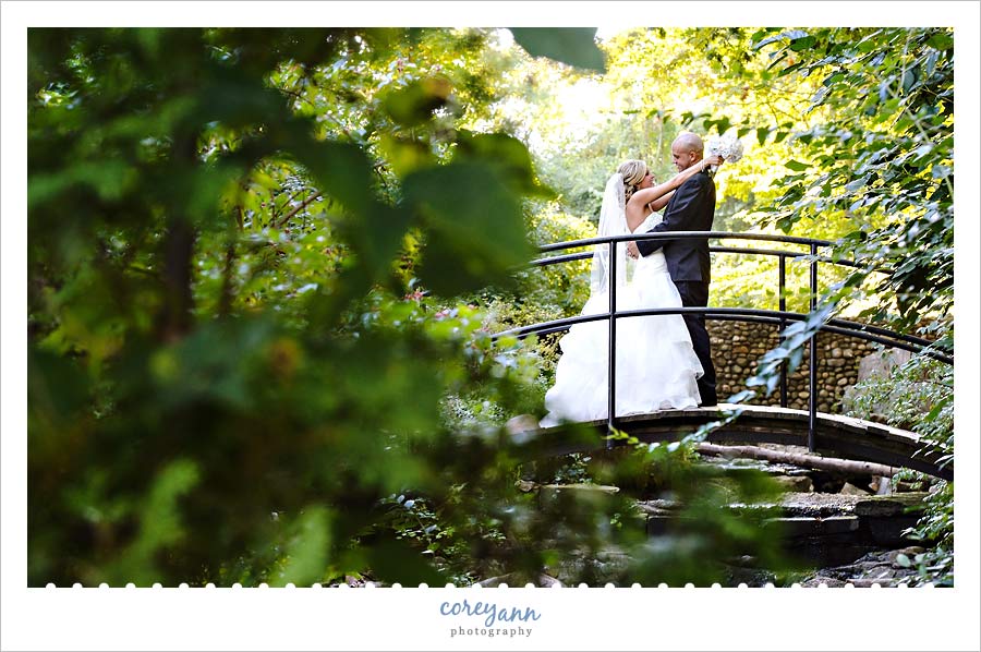 bride and groom posing on a bridge in a forest