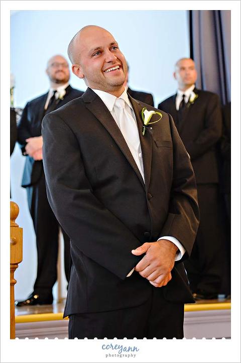 groom smiling when he sees his bride walking down the aisle