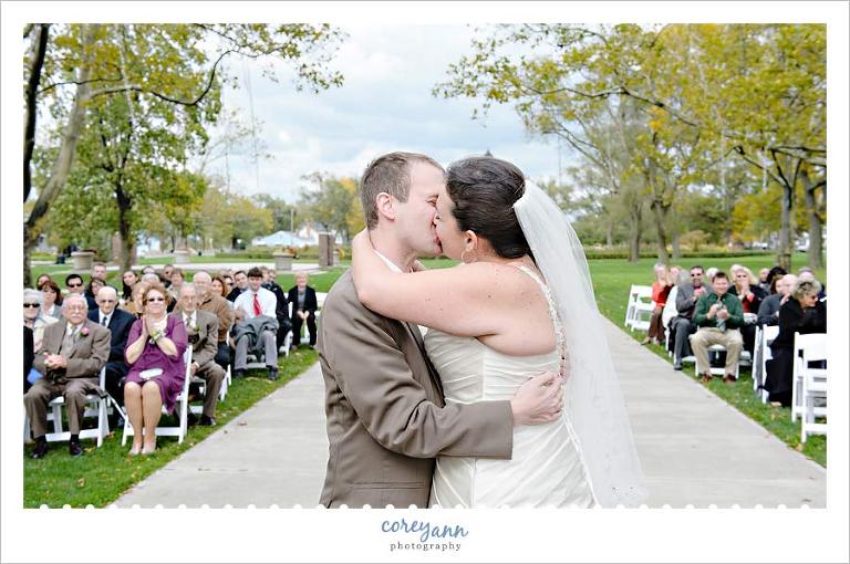 bride and groom first kiss with photo facing the guests