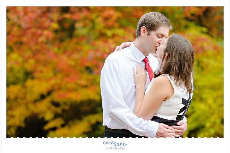 engaged couple kissing with leaves as a backdrop in canton ohio