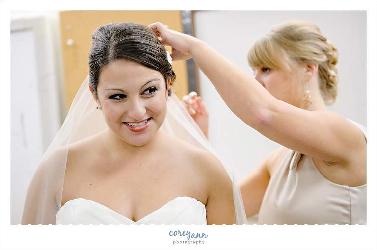 bridesmaid helping put veil on bride in north olmsted ohio