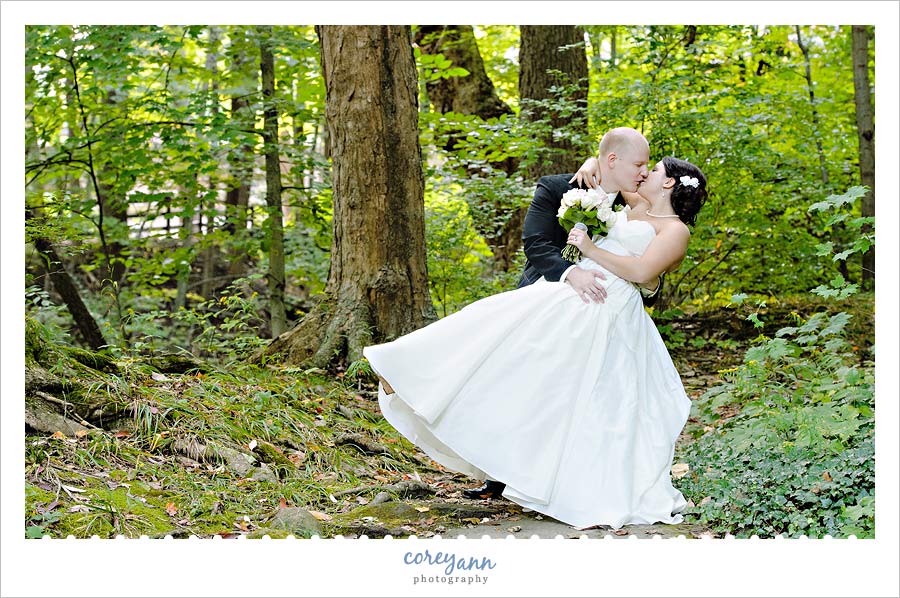 groom dipping bride in forest