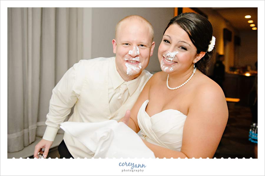 bride and groom with wedding cake smashed on their faces
