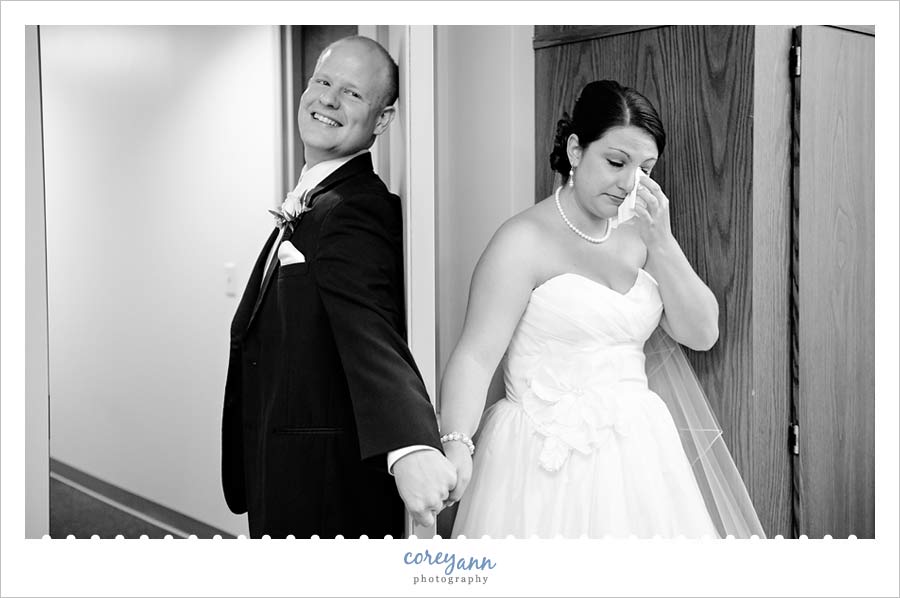 bride and groom holding hands behind door before ceremony