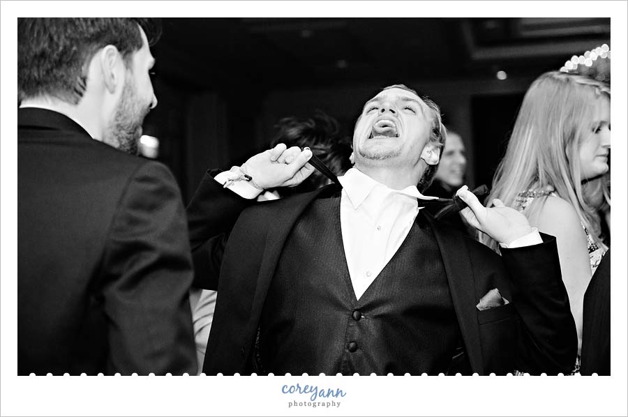 groomsman taking off bowtie on dance floor