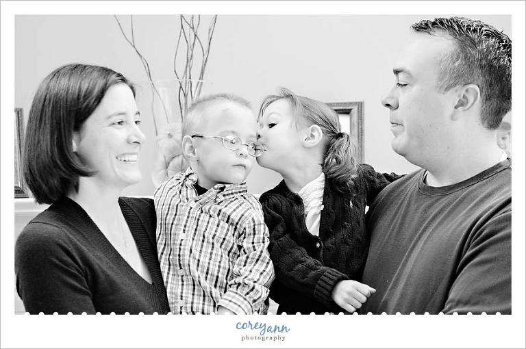 sister kissing brother on cheek during family portrait