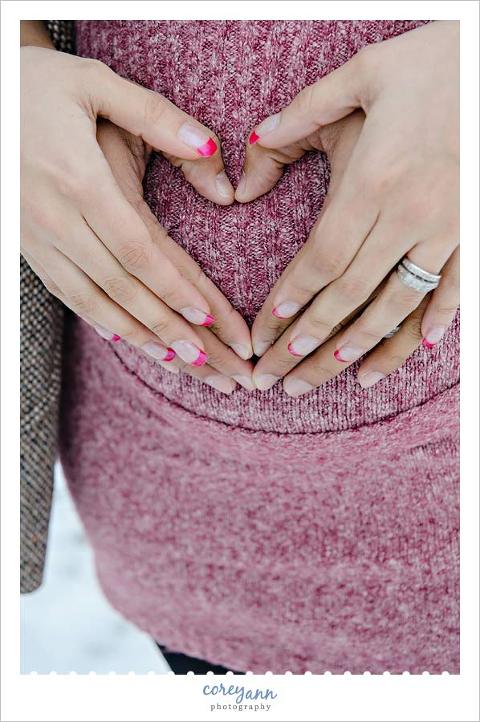 both parents hands over pregnant belly in a heart shape