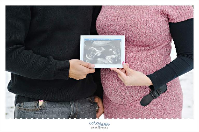 parents holding the sonogram of the baby to be in maternity session