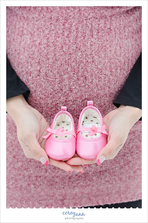 mom to be holding baby shoes during maternity session in canton ohio