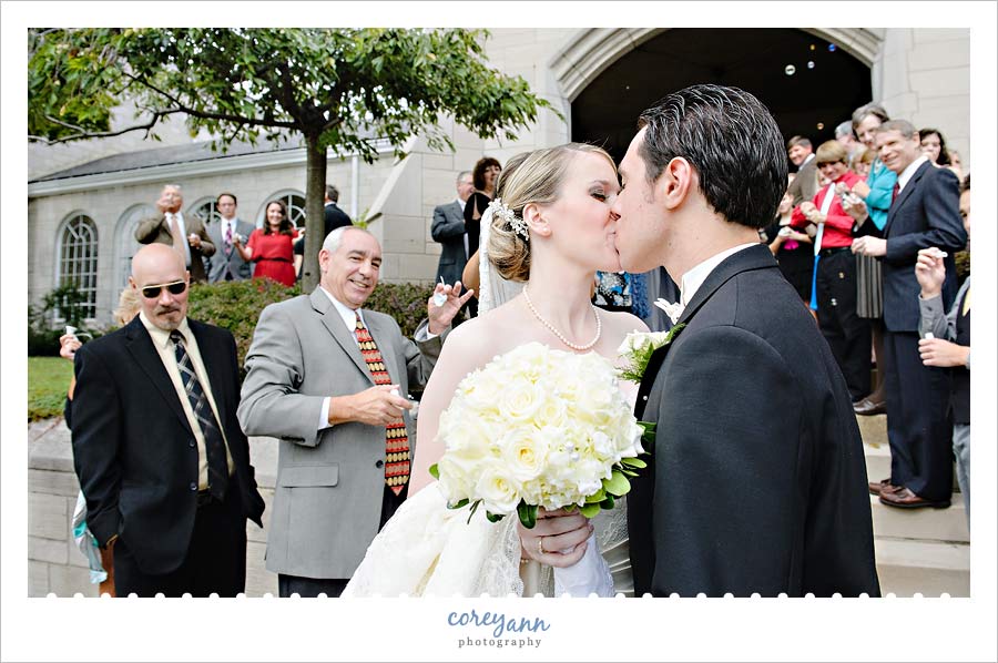 bride and groom kissing after exit from church in Ohio