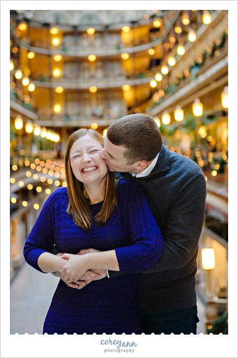 giggling during an engagement session at christmas in the hyatt arcade cleveland