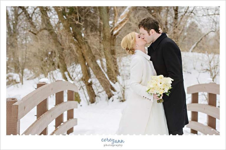 bride and groom kissing on a snow covered bridge in ohio