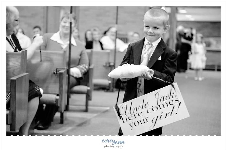ring bearer carrying sign here comes your girl