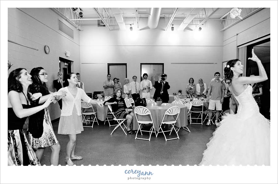 bride tossing her bouquet to guests during wedding reception