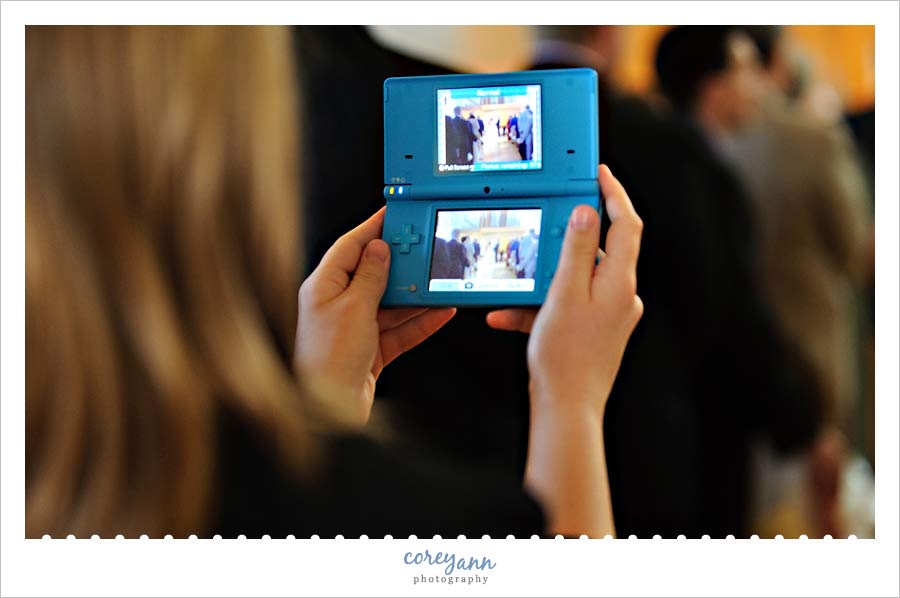 Unplugged Wedding guest using nintendo ds to take pictures during wedding ceremony