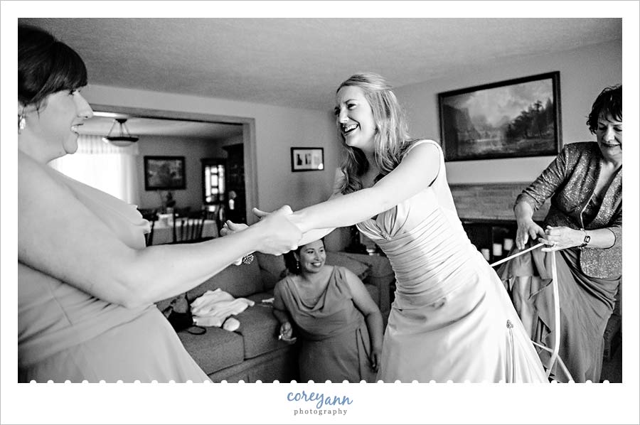 bride's mother and maid of honor helping with corset dress