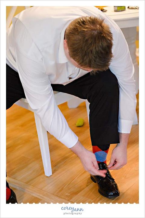 groom putting on ohio state themed socks for wedding