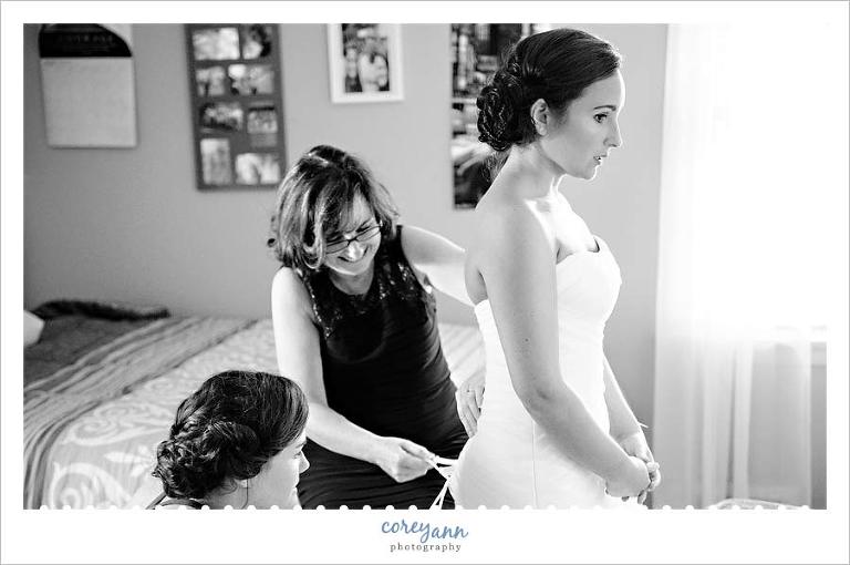 mother and sister helping bride with corset in wedding dress
