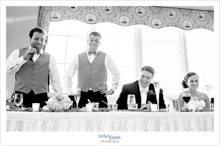 two best men giving wedding toast to bride and groom at reception