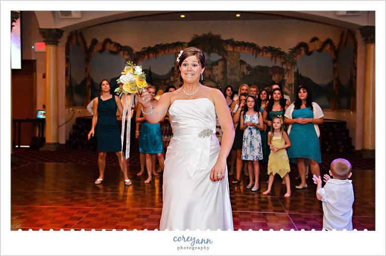 bride tossing her bouquet at wedding reception