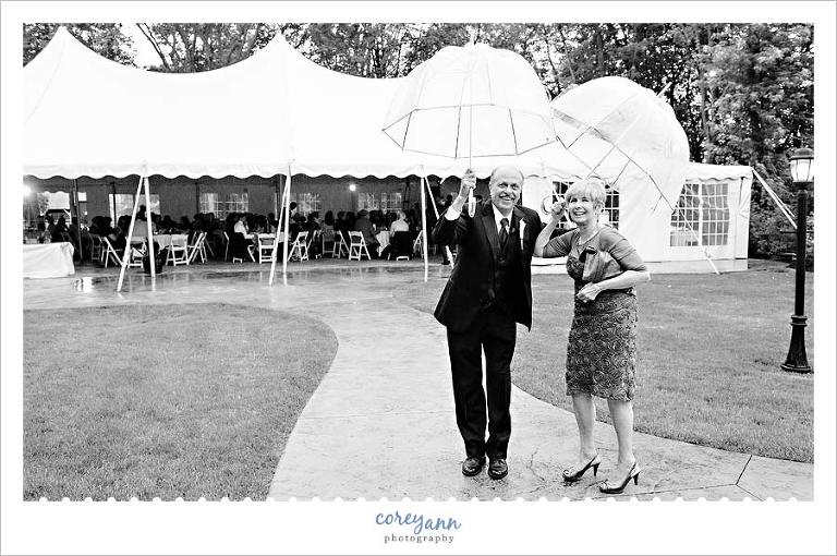 guests pose with umbrellas during rainy outdoor wedding reception