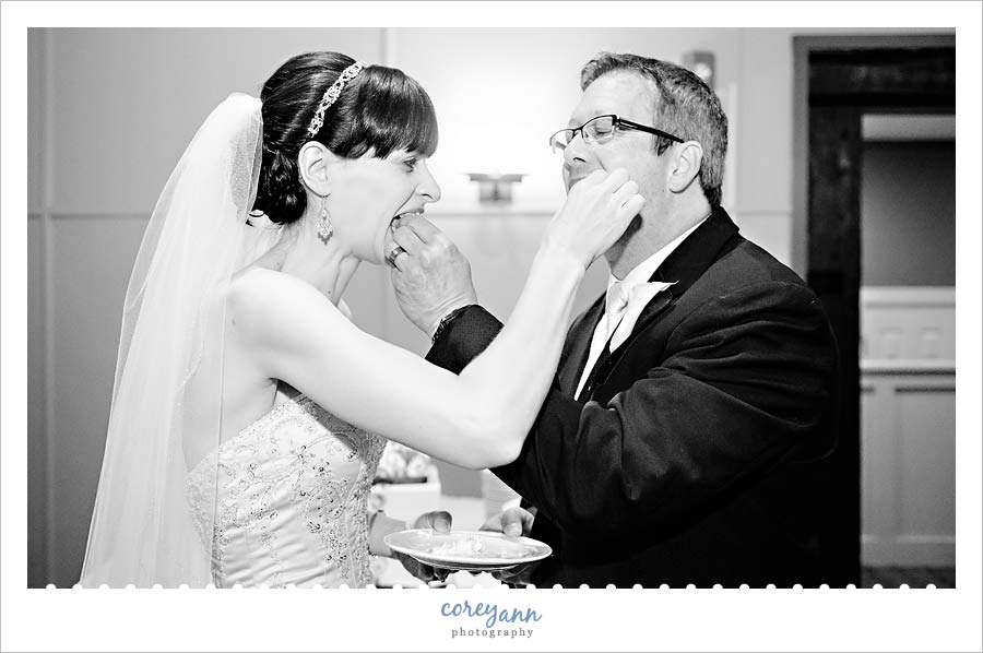 bride and groom feeding each other cake at wedding reception