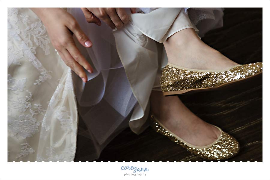 bride putting on gold glitter flats 