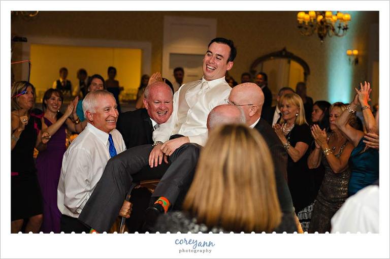 groom in chair during hora at westwood country club