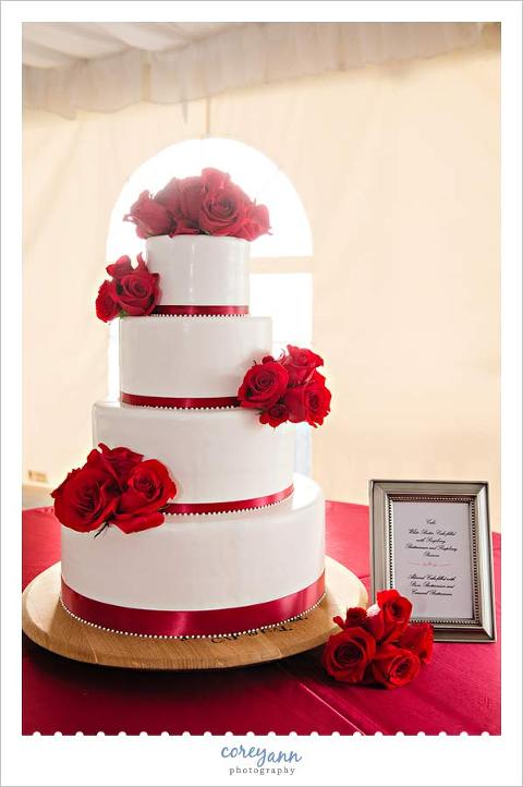 white cake with red roses and ribbon by wendy kromer confections
