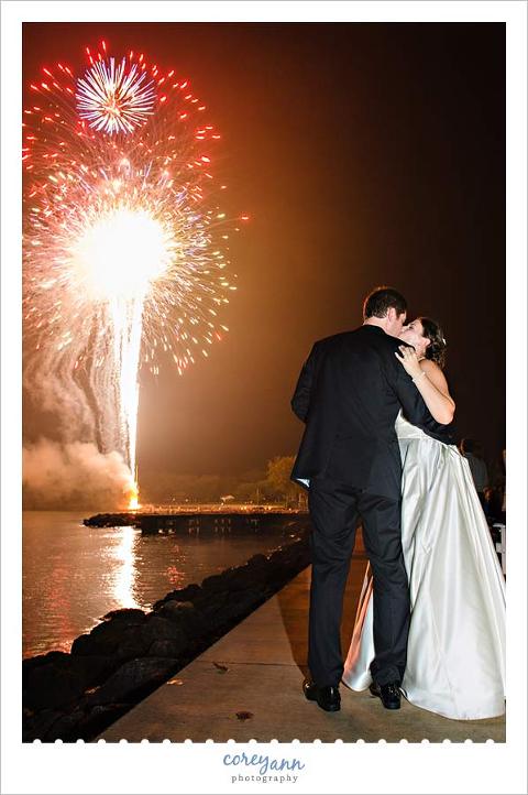 bride and groom kissing while fireworks go off