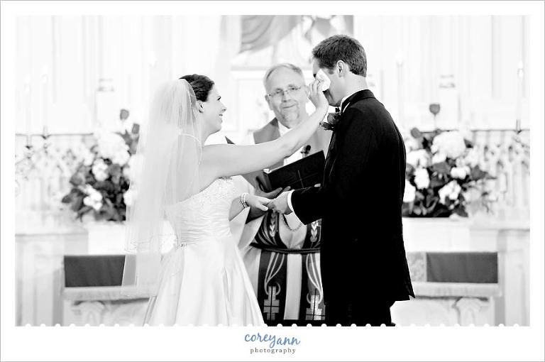 bride wiping tear from groom's eye during the ceremony
