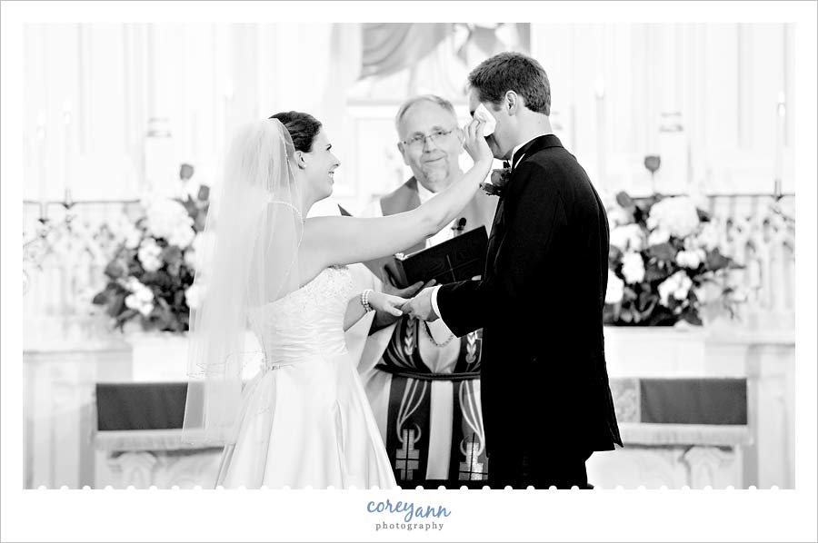 bride wiping tear from groom's eye during the ceremony