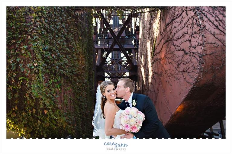 groom kissing bride on cheek on bridge in cleveland