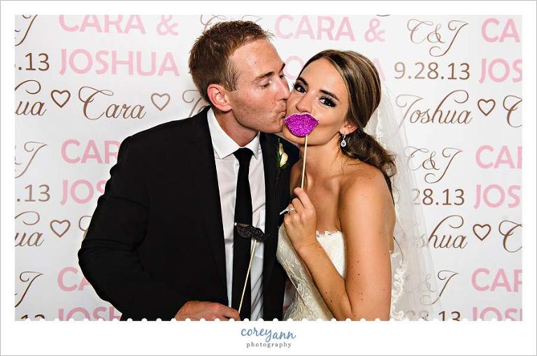 bride and groom pose in front of custom backdrop