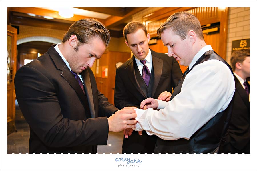 groomsman helping groom put on cufflinks