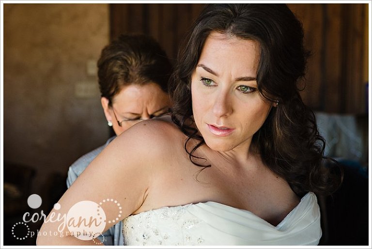 bride's mother helping her get dressed before wedding ceremony