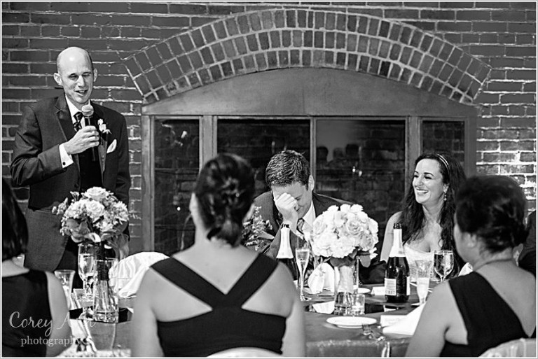 groom laughing during toast at wedding reception