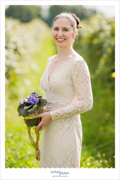 bride wearing gold lace dress with live violet floral bouquet