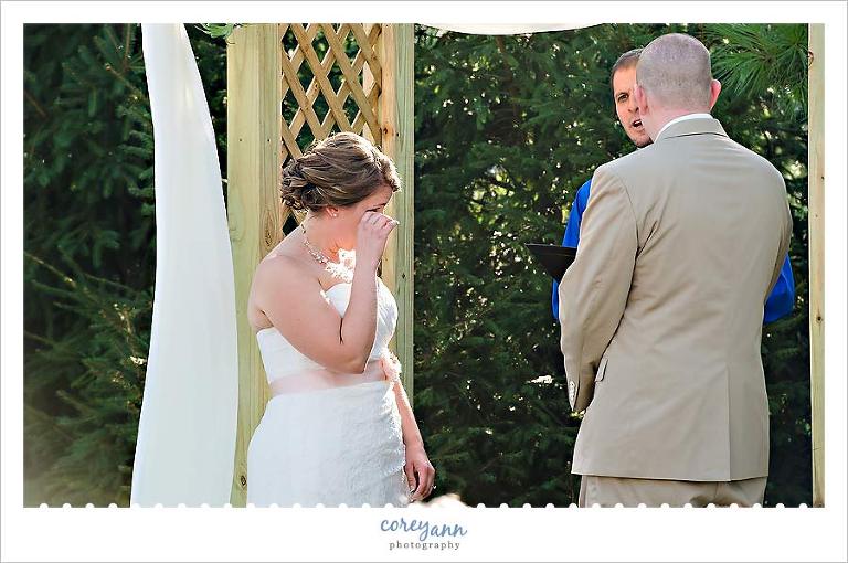 bride wiping away a tear during wedding ceremony