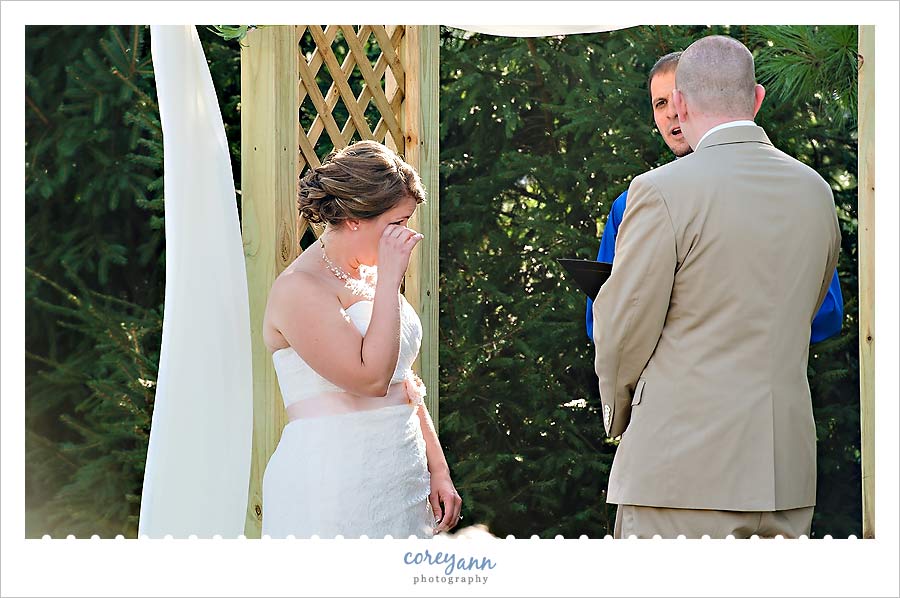 bride wiping away a tear during wedding ceremony